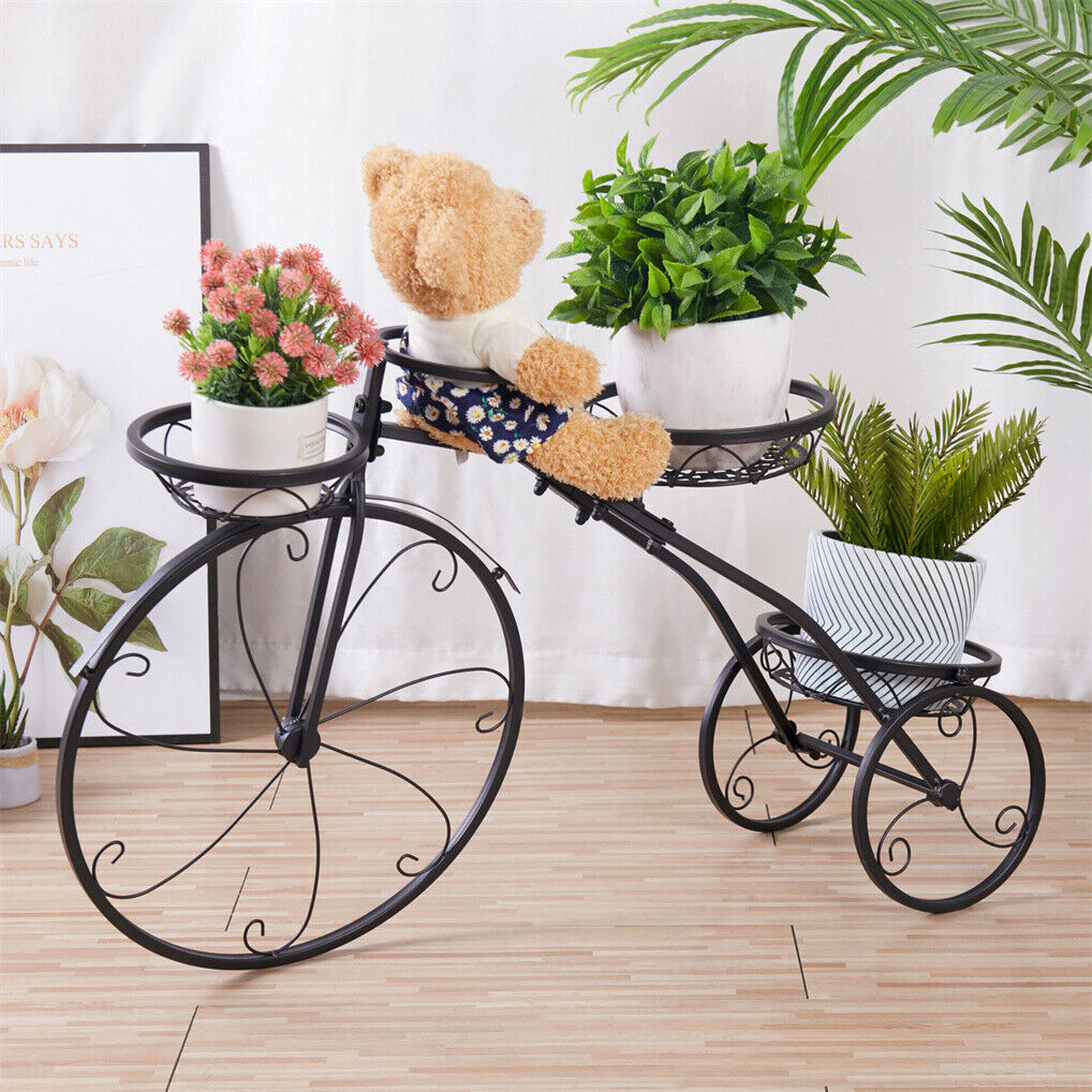 Black iron tricycle plant stand with faux greenery, decorative home and garden accessory for displaying artificial plants.