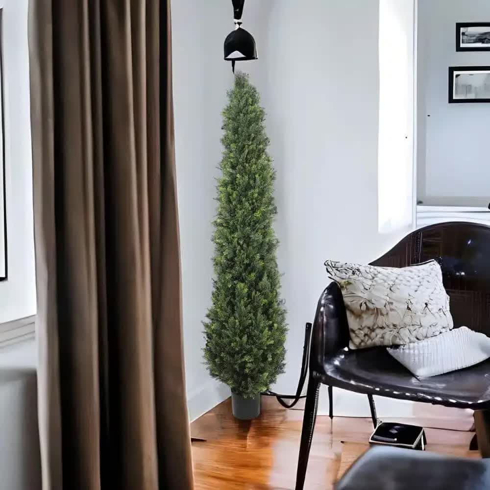 Living room with a tall artificial Christmas tree, brown curtain, and black chair.